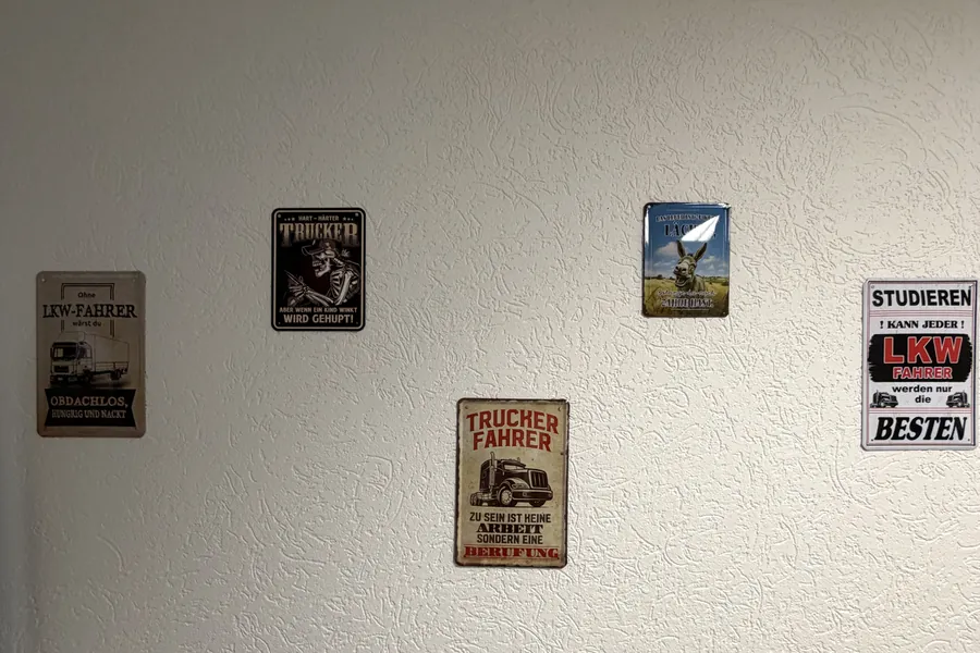 Tin signs with sayings about lorry drivers on a white wall