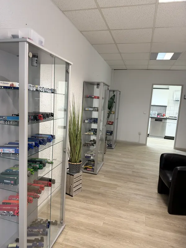 Hodnik s vitrinama punim modela kamiona i kožnim foteljama
