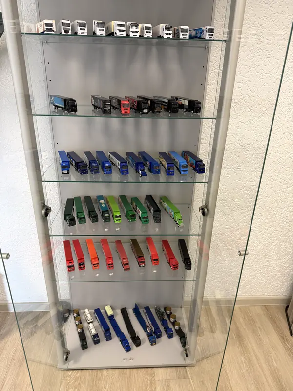 Glass display cabinet with model lorries, sorted by colour